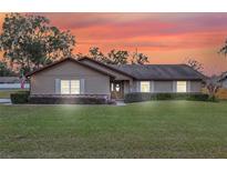 Ranch style home with a well-manicured lawn and beautiful sunset in the background at 4960 Se 37Th Ct, Ocala, FL 34480