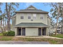 Two-story condo exterior with green siding and a covered entrance and mature landscaping at 6034 Westgate Dr # 202, Orlando, FL 32835