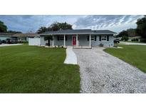 Cute ranch home with red door, landscaped lawn, and a gravel driveway at 6642 Matchett Rd, Orlando, FL 32809