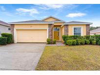 One-story house with a yellow exterior, a two-car garage, and well-manicured landscaping at 841 Greenshank Dr, Haines City, FL 33844