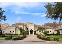 Grand two-story home with a tile roof, palm trees, and manicured landscaping at 9213 Foxhall Ct, Orlando, FL 32819