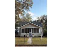 Charming bungalow with a screened front porch, walkway, and a well-maintained lawn under a canopy of mature trees at 113 W 19Th St, Sanford, FL 32771