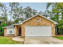 Brick house with a two-car garage and a well-manicured lawn at 1501 Red Oak Ct, Apopka, FL 32703