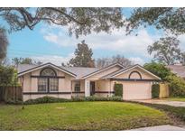 Single-story home with attached garage, well-manicured lawn, and mature trees at 4491 Yachtmans Ct, Orlando, FL 32812