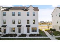 Three-story townhome with white siding, gray accents, and landscaping at 15100 Grove Lake Dr, Winter Garden, FL 34787