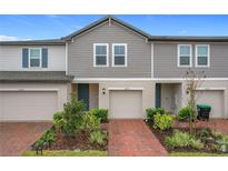 Two-story townhome with gray siding, brick pavers, and attached garage at 2038 Crape Jasmine Ln, Orlando, FL 32824