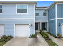 Townhouse exterior featuring a light blue facade, two-car garage and walkway at 2719 Bright Bird Ln, Winter Park, FL 32792
