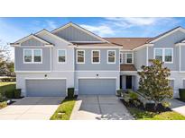 Two-story townhome with gray siding, two-car garage, and landscaping at 9218 Shepton St, Orlando, FL 32825