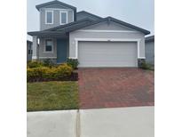 Two-story house with gray siding, brick driveway, and landscaping at 1341 Current Pl, Haines City, FL 33844