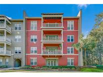 Three-story building with red exterior, balconies, and lush landscaping at 1410 Celebration Ave # 101, Celebration, FL 34747