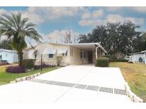 Single-wide manufactured home with carport and landscaped yard at 214 Covent Garden Ave, Davenport, FL 33897