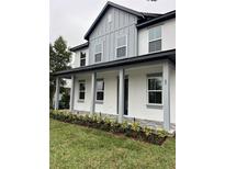 Two-story house featuring gray and white exterior, front porch, and landscaped lawn at 62 W Esther W St, Orlando, FL 32806