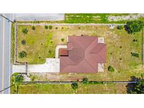 Aerial view of a house with a brown roof, surrounded by a well-maintained green lawn and a concrete driveway at 1719 North W Blvd, Davenport, FL 33837