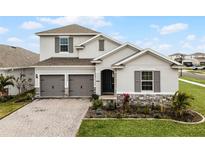 Two-story home with gray siding, two-car garage, and landscaped yard at 4558 Lions Gate Ave, Clermont, FL 34711