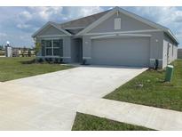Newly constructed home with gray exterior, two-car garage, and well-manicured lawn at 8864 Sw 49Th Cir, Ocala, FL 34476