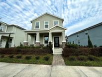 Inviting two-story home featuring a covered front porch with stately columns and manicured landscaping at 9741 Petition Way, Orlando, FL 32832