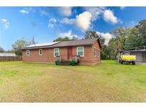 Cozy single-story home featuring solar panels, red front door, and a spacious green lawn at 9877 7Th Ave, Orlando, FL 32824