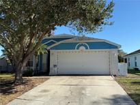 Cute blue house with a white garage door and well-maintained lawn at 154 Woodbury Pines Cir, Orlando, FL 32828