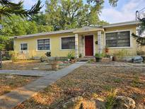 Cute yellow house with red door, landscaping, and walkway at 6254 Balboa Dr, Orlando, FL 32808