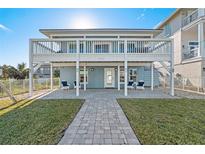 Charming home featuring a covered patio, well-maintained lawn, and beautiful paver walkway at 6912 S Atlantic Ave, New Smyrna Beach, FL 32169