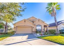 Tan one-story house with a two-car garage and landscaped yard at 2132 Darlin Cir, Orlando, FL 32820