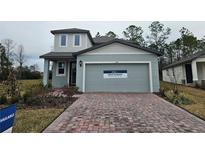 Move-in ready two-story home with a gray exterior, brick driveway and landscaping at 224 Links Terrace Blvd, Daytona Beach, FL 32124