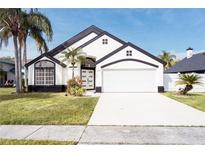 White two-story house with black accents, two-car garage, and palm trees at 2319 Island Club Way, Orlando, FL 32822
