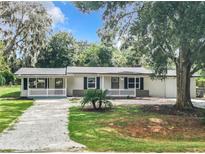 Newly renovated home with a white exterior, landscaping, and a gravel driveway at 36810 Lake Unity Rd, Fruitland Park, FL 34731