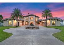 Elegant two-story home with fountain and palm trees at dusk at 5251 Carson St, St Cloud, FL 34771