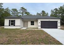 Charming single-story home with a dark gray roof, complemented by an attached two-car garage and a well-manicured lawn at 14735 Sw 69Th Court Rd, Ocala, FL 34473
