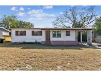 Ranch-style home featuring a white exterior, brown door, and carport at 5702 Meridian Way, Orlando, FL 32808