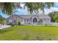 Charming single-story home with manicured lawn, white picket fence, and arched windows at 17901 Coralwood Ln, Groveland, FL 34736