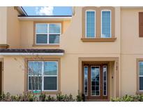 Tan two-story townhome with brown door and landscaping at 2182 Fleming Mist Pl, Kissimmee, FL 34747