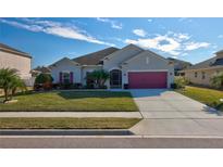 Single-story house with a gray exterior, pink garage door, and well-manicured lawn at 2518 Hayden Valley St, Apopka, FL 32703