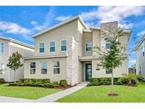 Contemporary two-story home with stone accents, manicured lawn, and inviting blue front door at 3012 Penelope Loop, Kissimmee, FL 34746