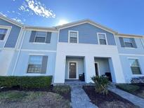 Two-story townhome with blue siding, walkway, and landscaping at 8902 Sydney Ave, Kissimmee, FL 34747