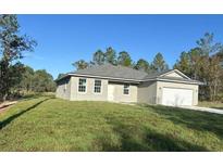 One-story home with gray siding, attached garage, and grassy yard at 8944 Sw 128Th Pl, Ocala, FL 34473