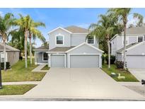 Two-story house with gray siding, three-car garage, and palm trees at 9856 Heron Pointe Dr, Orlando, FL 32832