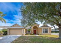 Charming single-story home with a well-maintained lawn, red front door, and attached two car garage at 405 Kehoe Blvd, Orlando, FL 32825