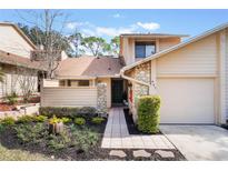 Tan two-story townhome with a paved walkway, landscaping, and attached garage at 447 Stanton Pl, Longwood, FL 32779