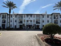 Resort-style condo building with palm trees and brick driveway at 5550 E Michigan St # 2223, Orlando, FL 32822