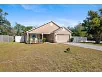 One-story house with tan exterior, front porch, and landscaped yard at 110 Oak St, Clermont, FL 34711