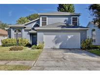 Two-story house with gray siding, white garage door, and landscaped lawn at 13111 Point O Wood Ct, Orlando, FL 32828