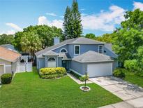 Charming two-story home with a manicured lawn, lush landscaping, and an attached two-car garage at 13111 Point O Wood Ct, Orlando, FL 32828