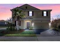 Two-story house with a tan exterior, brown accents, and a paved driveway at 1504 Oak Marsh Loop, Davenport, FL 33837