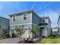 Two-story house with light blue siding, two-car garage, and a landscaped front yard at 1611 Kona Ln, Davenport, FL 33897