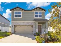 Two-story house with stone accents and a two-car garage at 1991 Hemingway Cir, Groveland, FL 34736