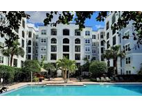 Resort-style pool at a condo complex, surrounded by lounge chairs, palm trees, and a tiki bar at 202 E South St # 1050, Orlando, FL 32801