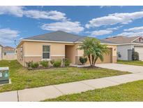 Beige house with gray roof, palm tree, and a two-car garage at 213 Lake Lucerne Way, Winter Haven, FL 33881