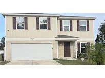 Two-story house with beige siding, brown shutters, and a two-car garage at 233 Gladiola Ct, Poinciana, FL 34759